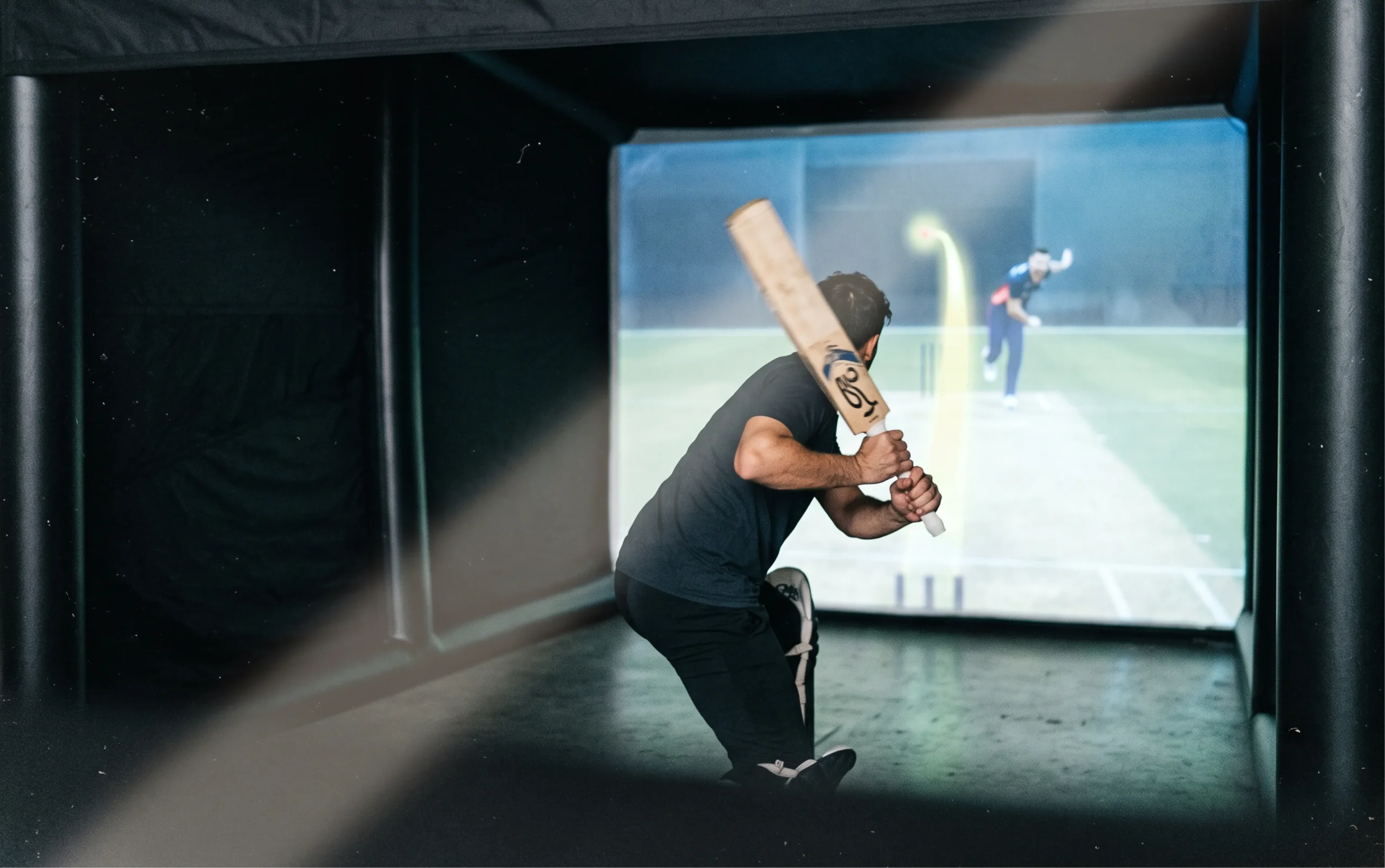 Cricket batter preparing to face a delivery inside a simulator bay